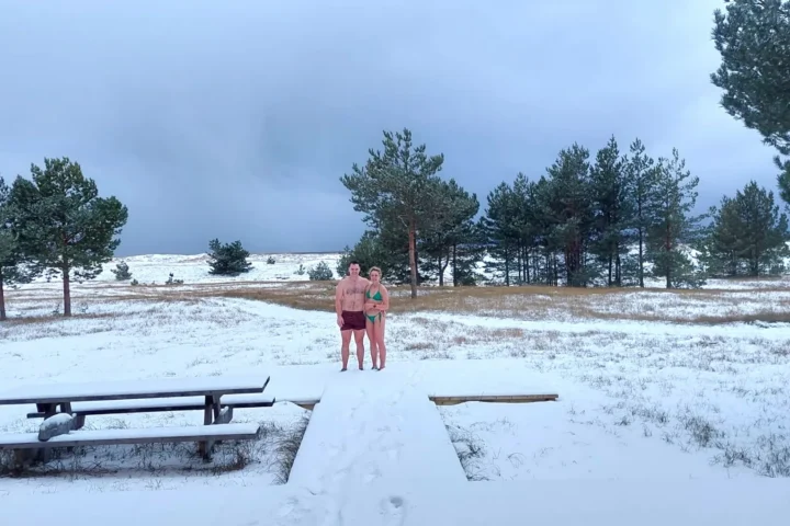 Couple standing in swimwear on a snowy Prangli Island landscape after winter sauna experience