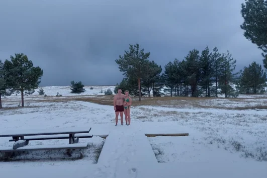 Couple standing in swimwear on a snowy Prangli Island landscape after winter sauna experience