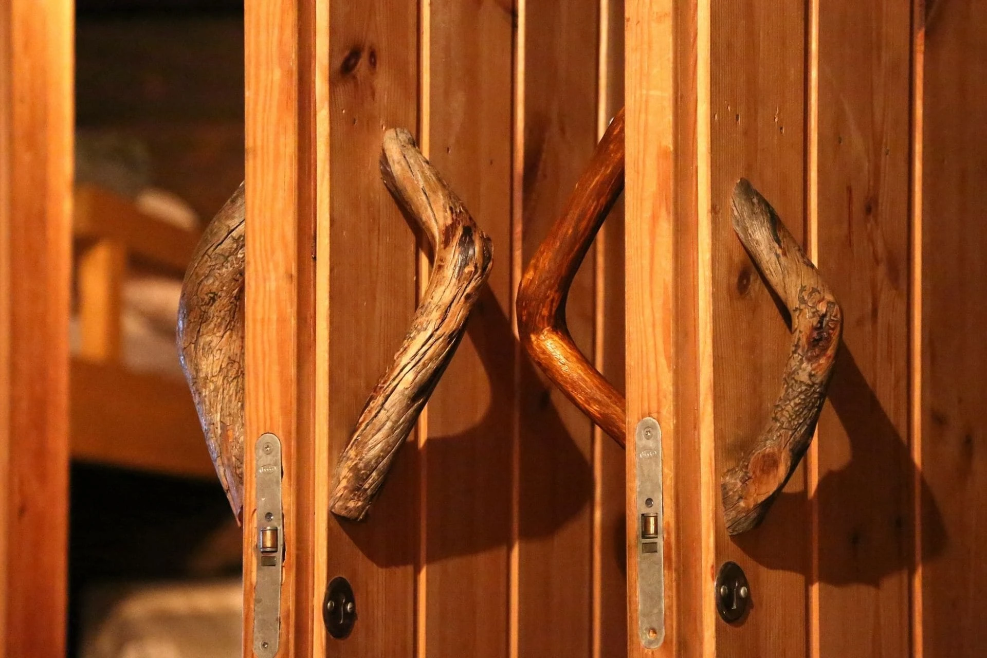 Wooden Estonian sauna doors with rustic curved branch handles leading to the changing room