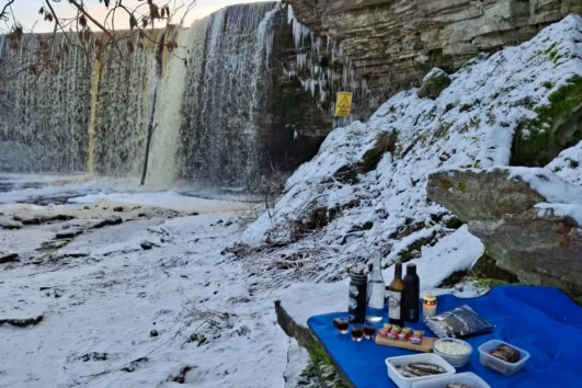 Winter picnic setup by the partially frozen Jägala Waterfall in Estonia