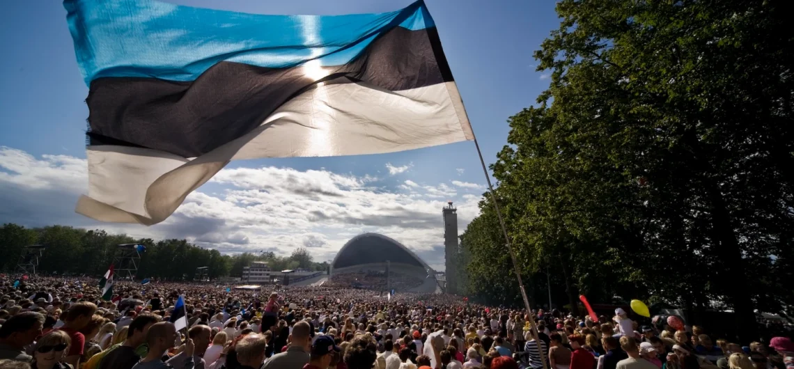 Estonian flag waving above a large crowd at the Estonian Song Festival in Tallinn
