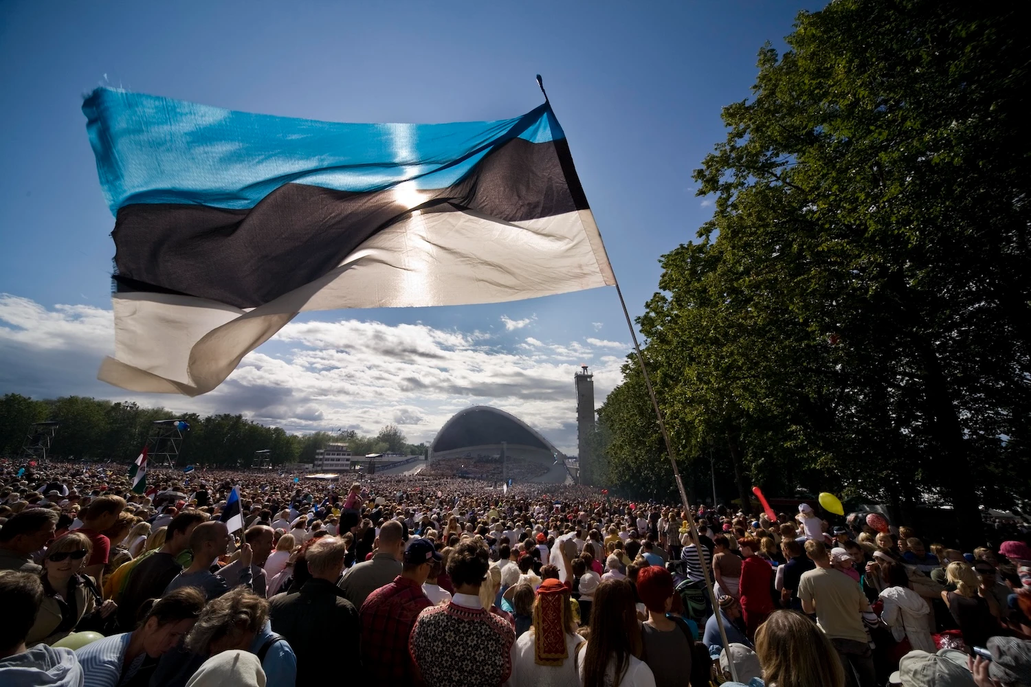 Estonian flag waving above a large crowd at the Estonian Song Festival in Tallinn