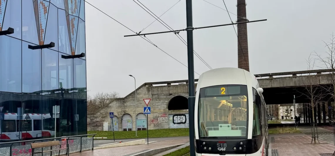 Modern red-and-white Tallinn tram passing a glass building in the urban centre
