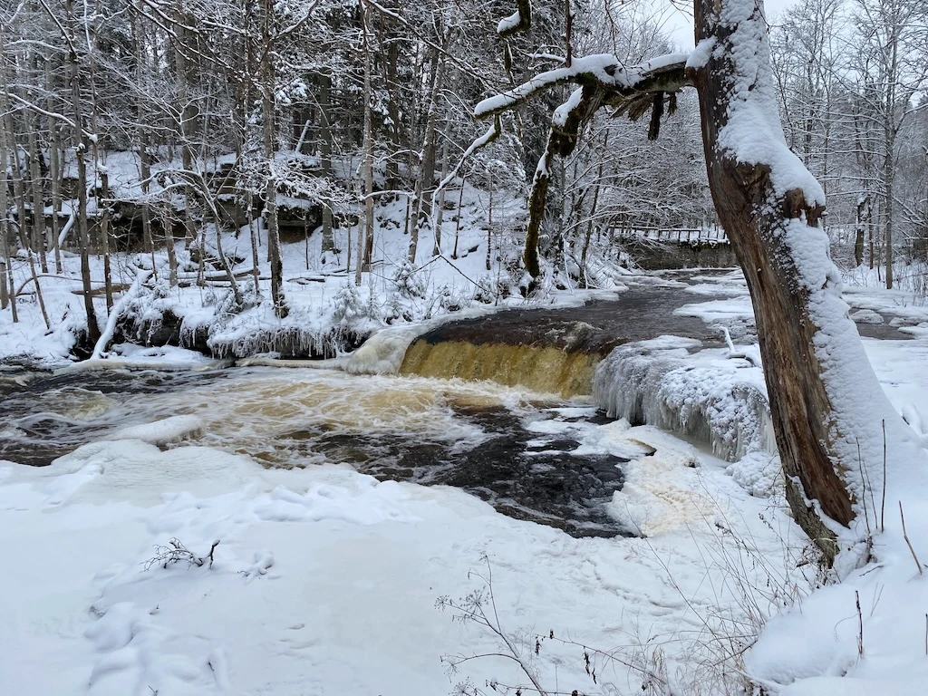Nõmmeveski waterfall in winter surrounded by snow-covered forest in North Estonia