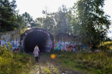 Visitor entering an abandoned Soviet-era rocket base tunnel hidden in the Viimsi peninsula forest.