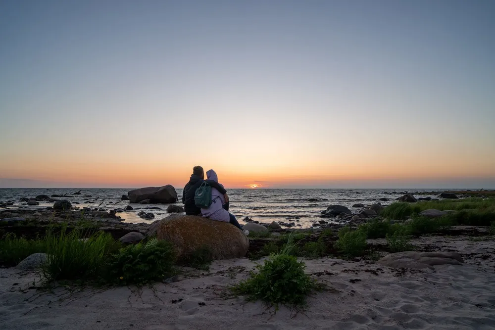 Two people sitting on a boulder watching the sunset on Prangli Island.