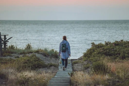 Woman walking on a wooden boardwalk to the sea on Prangli Island
