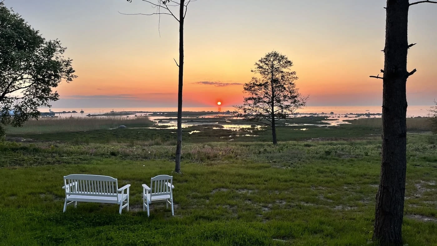 Sunset over the Baltic Sea at Villa of Nature Energy Prangli Island with garden benches facing the coast