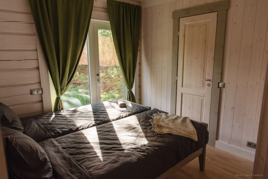 Twin bedroom at Villa of Nature Energy Prangli Island with garden view and green linen curtains