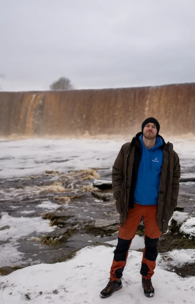 Andreas, tour guide at Prangli Travel, standing in front of a frozen waterfall in winter Estonia