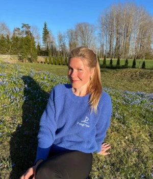 Berit, tour guide at Prangli Travel, sitting in a green Estonian meadow in spring sunshine