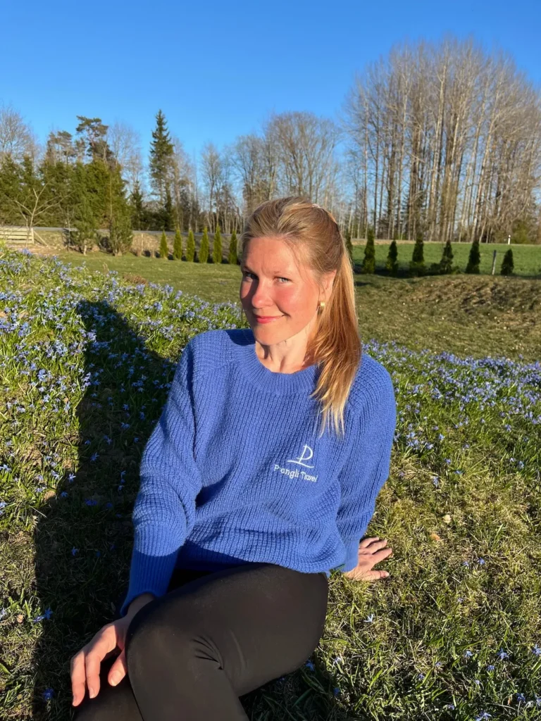 Berit, tour guide at Prangli Travel, sitting in a green Estonian meadow in spring sunshine