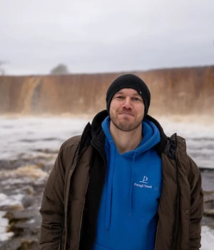 Andreas, tour guide at Prangli Travel, standing in front of a frozen waterfall in winter Estonia