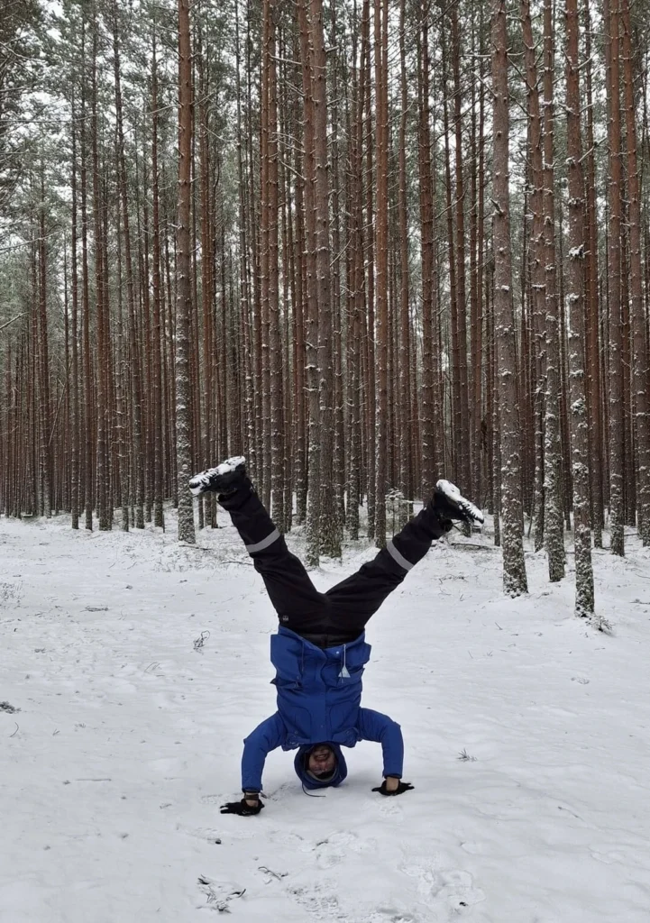 Jorge, tour guide at Prangli Travel, doing a handstand in a snowy Estonian pine forest